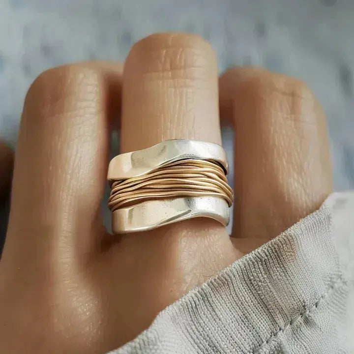 Gold and silver ring on a finger with a blurred background