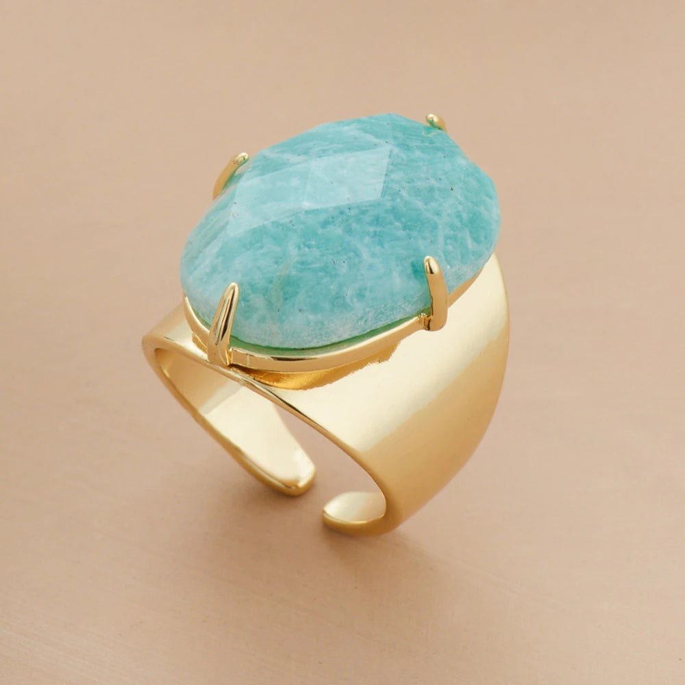 Gold ring with a large turquoise stone on a beige background