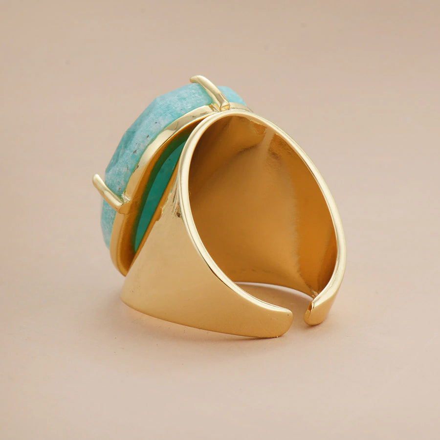 Gold ring with turquoise stone on a beige background