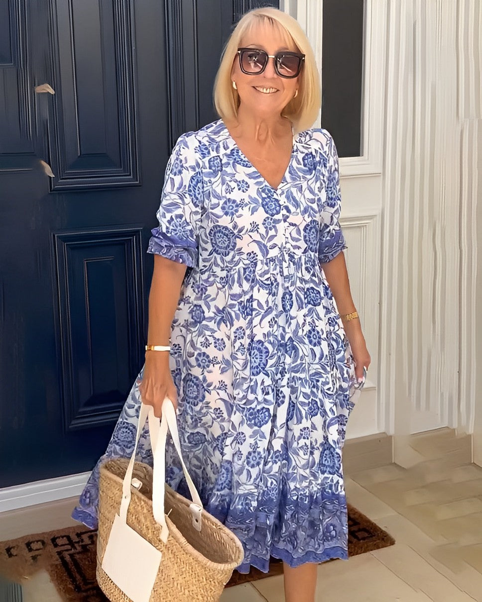 Woman in a blue floral dress standing in front of a dark blue door.
