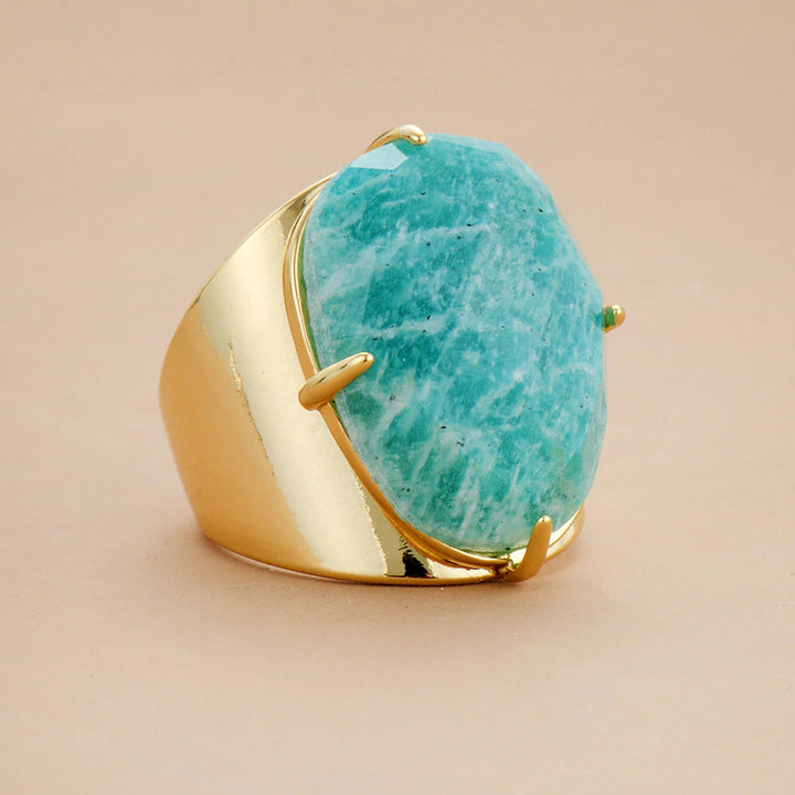 Gold ring with a large turquoise stone on a beige background