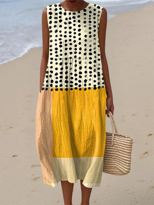 Woman wearing a polka dot dress with a yellow skirt on a beach.