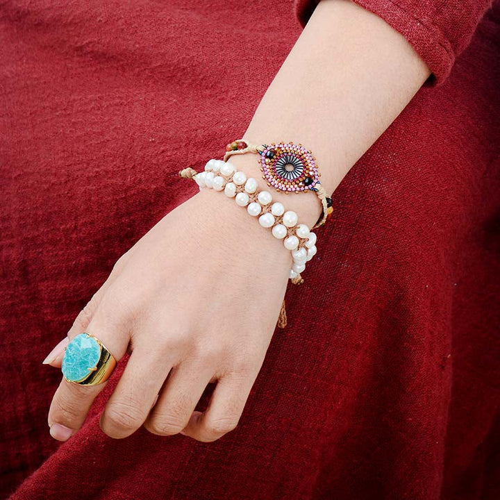 Hand wearing a bracelet with a red garment in the background