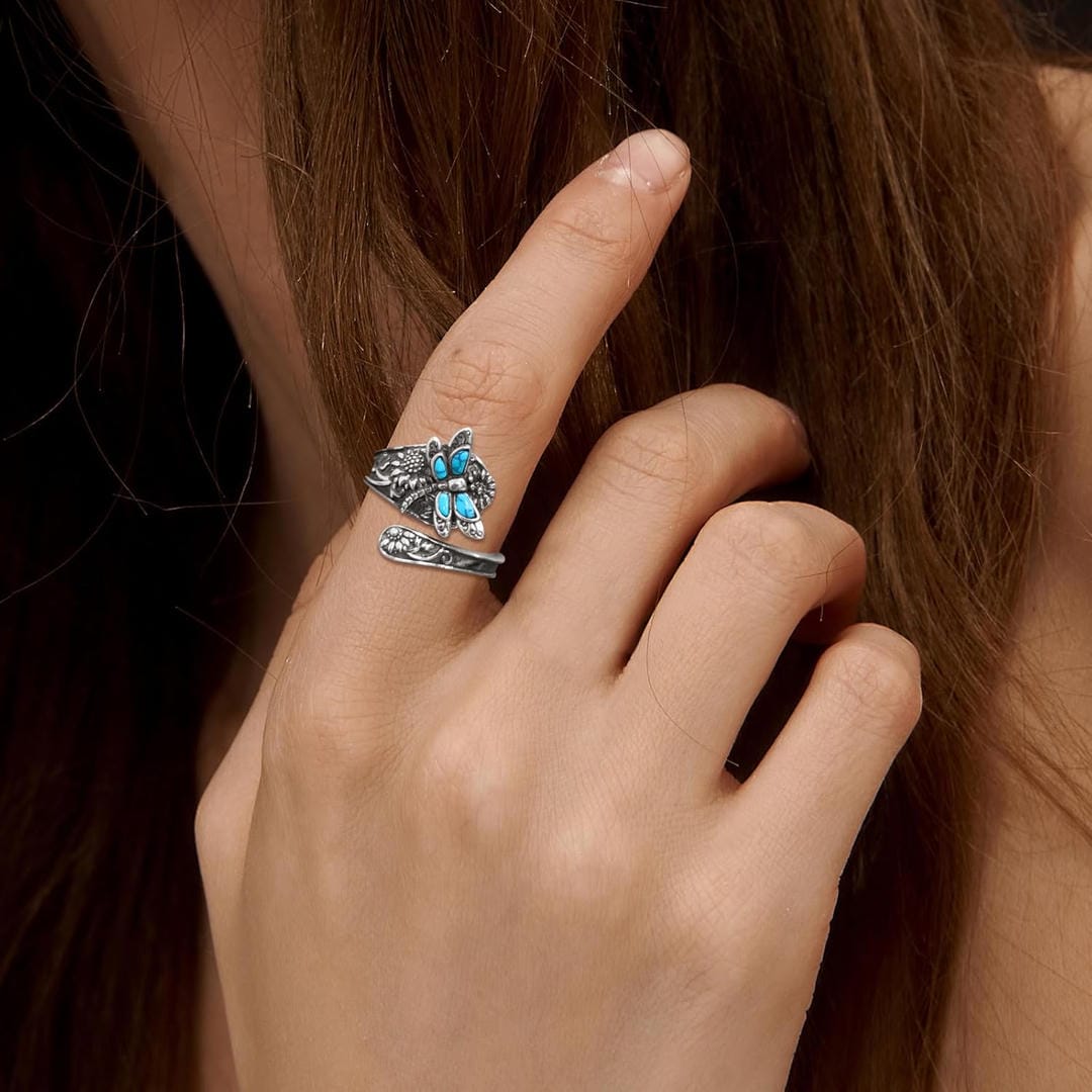 Close-up of a hand wearing a decorative ring with turquoise stones, holding hair.