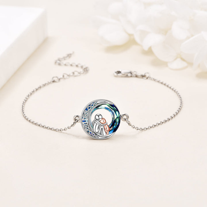 Silver bracelet with a circular charm featuring an illustration of a couple, on a light background.