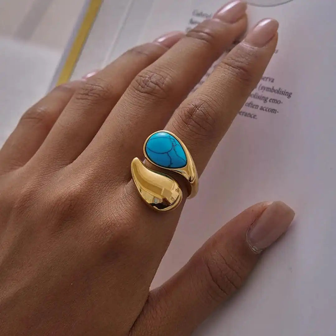 Gold ring with a turquoise stone on a hand against a blurred background