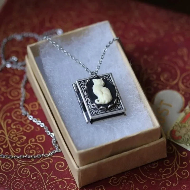 Necklace with a cat pendant in a decorative box on a red patterned fabric background