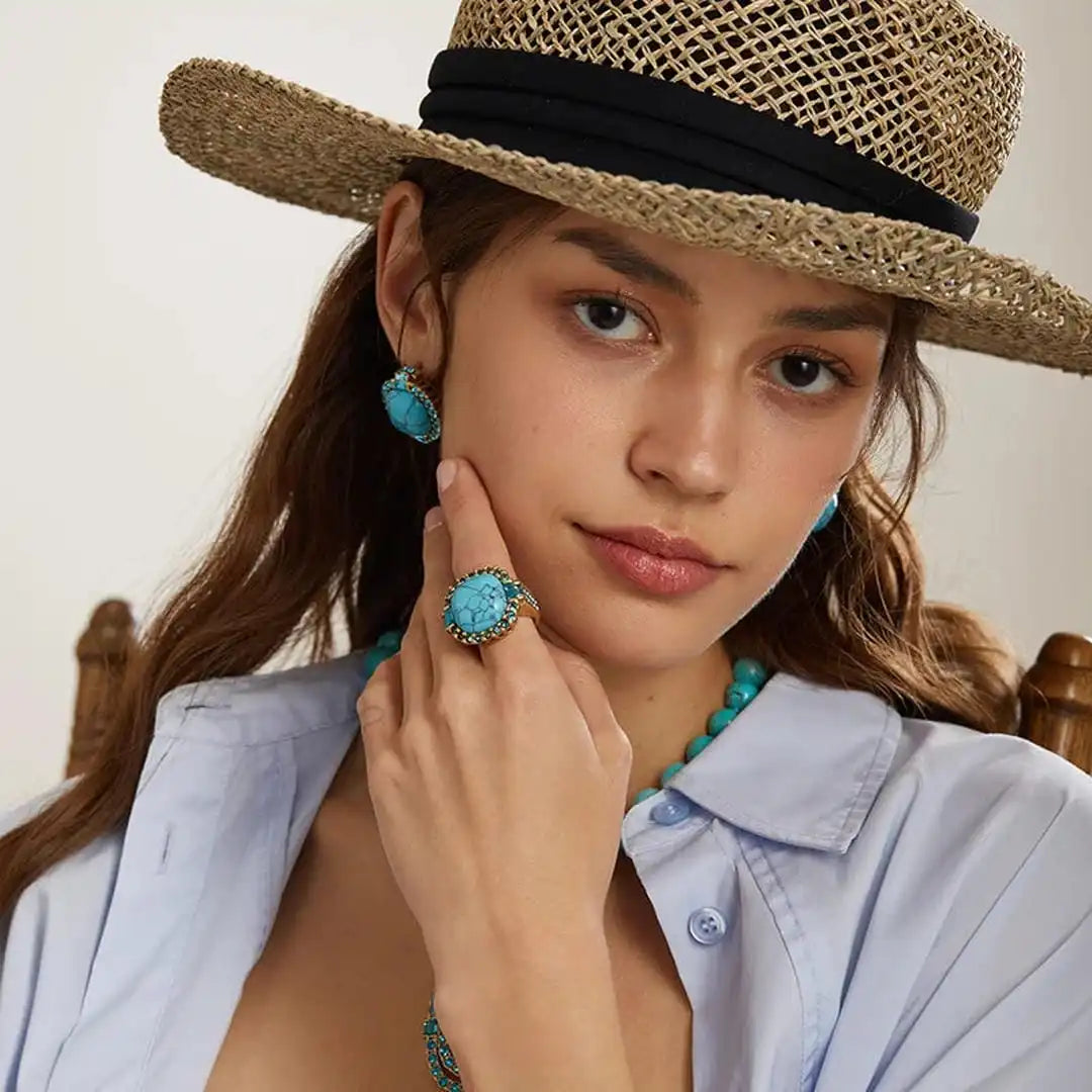 Woman wearing a straw hat, turquoise jewelry, and a light blue shirt.