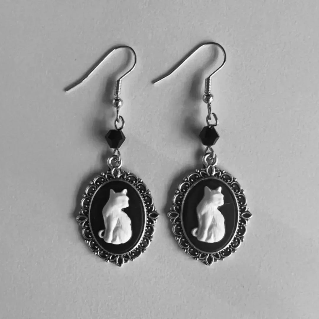 Cat-themed earrings with black and white designs on a gray background