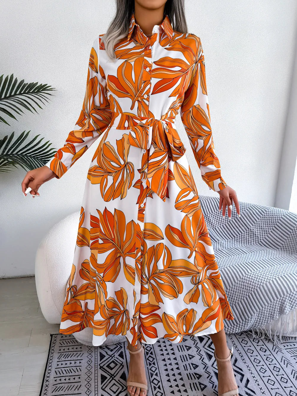 Woman wearing an orange and white floral dress in a modern room.