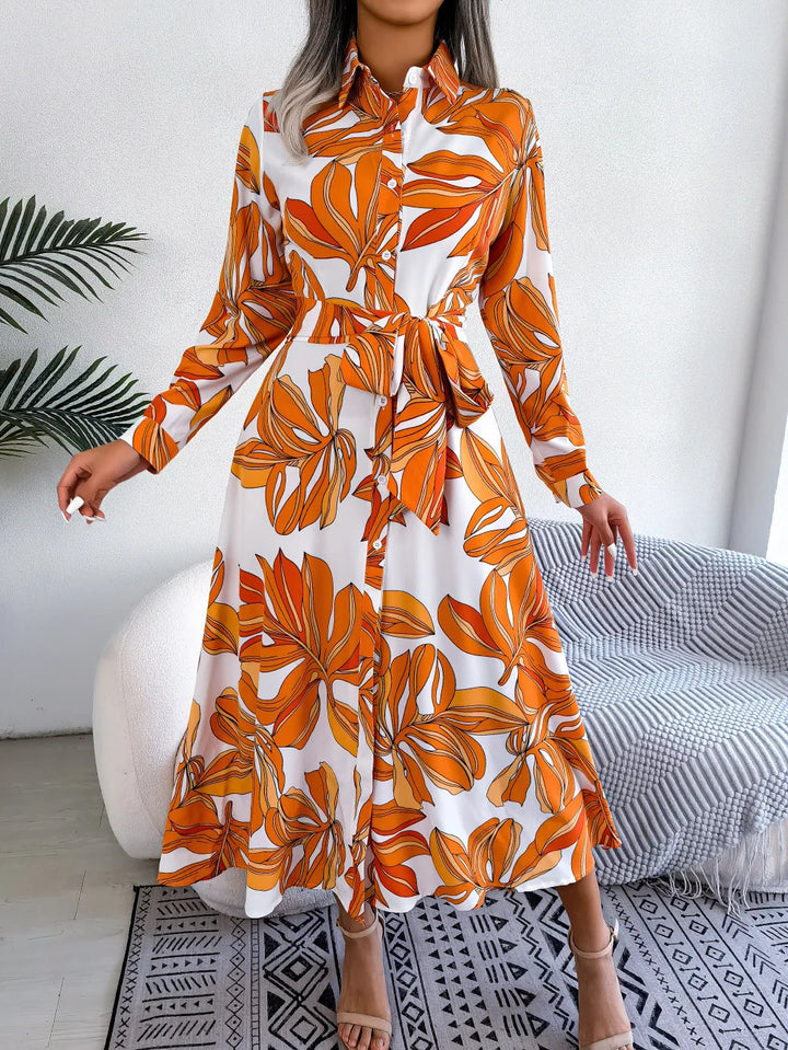 Woman wearing an orange and white floral dress in a modern room.