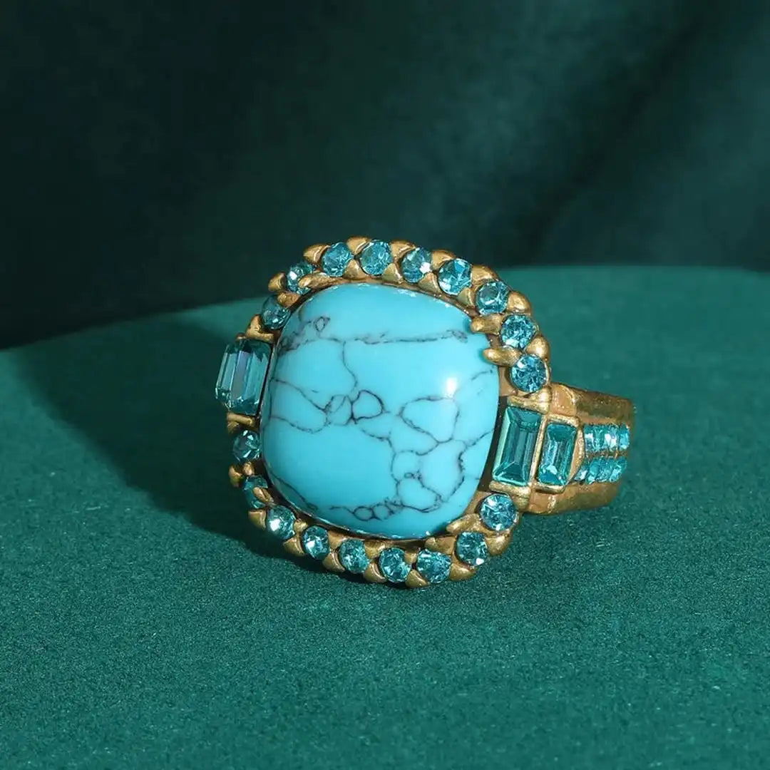 Gold ring with turquoise stone and gemstones on a green background