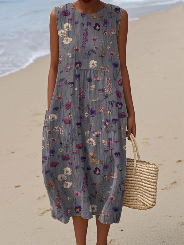 Woman in a floral dress holding a straw bag on a beach.