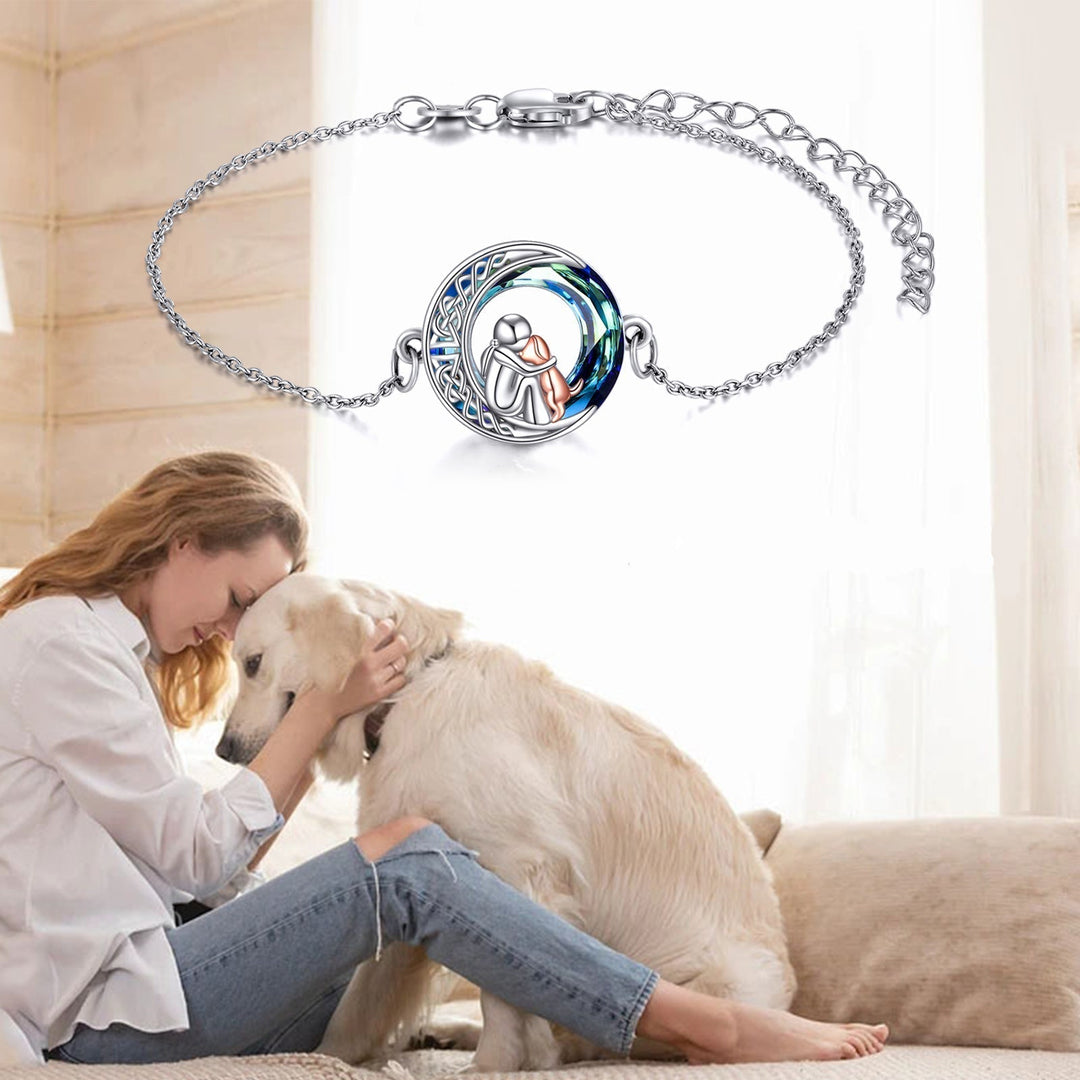 Woman hugging a dog with a silver bracelet featuring a round pendant on a white background