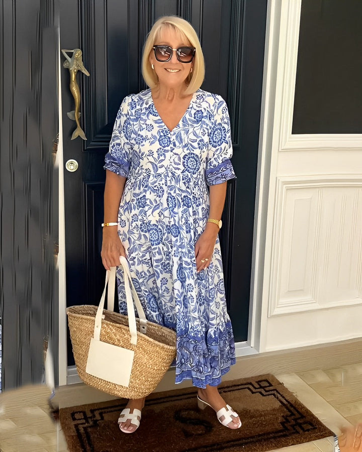 Woman in a blue and white dress standing in front of a black door.