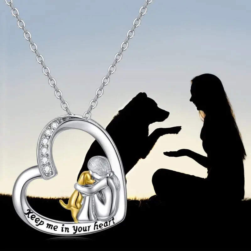 Heart-shaped pendant with a dog and person design, featuring the text 'Keep me in your heart', against a silhouette of a woman and dog.