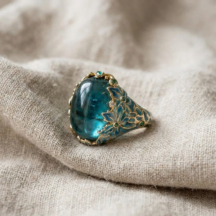 Blue gemstone ring with gold detailing on a beige fabric background