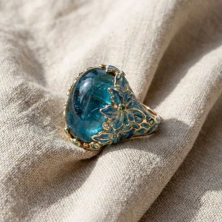 Blue gemstone ring with gold detailing on a beige fabric background