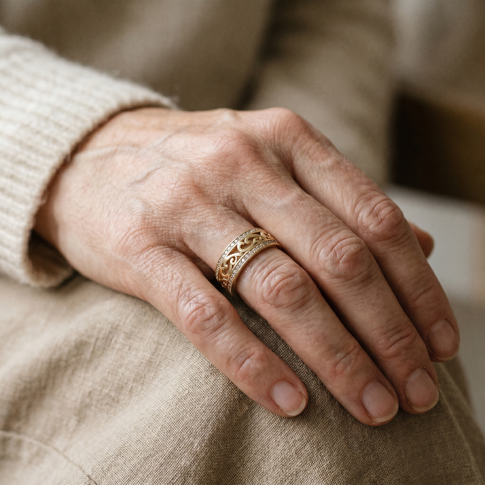 Close-up of a hand wearing a gold ring on a beige fabric background