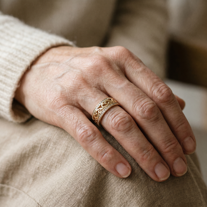 Close-up of a hand wearing a gold ring on a beige fabric background