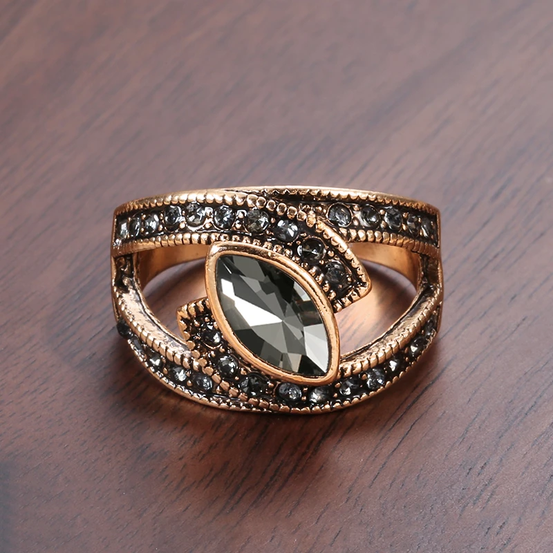 Gold ring with a central gemstone and smaller stones on a wooden surface