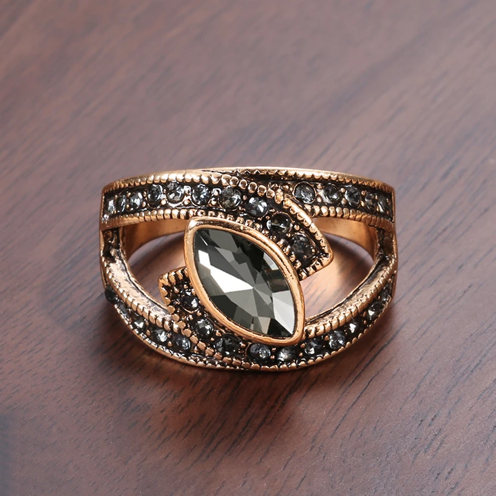 Gold ring with a central gemstone and smaller stones on a wooden surface