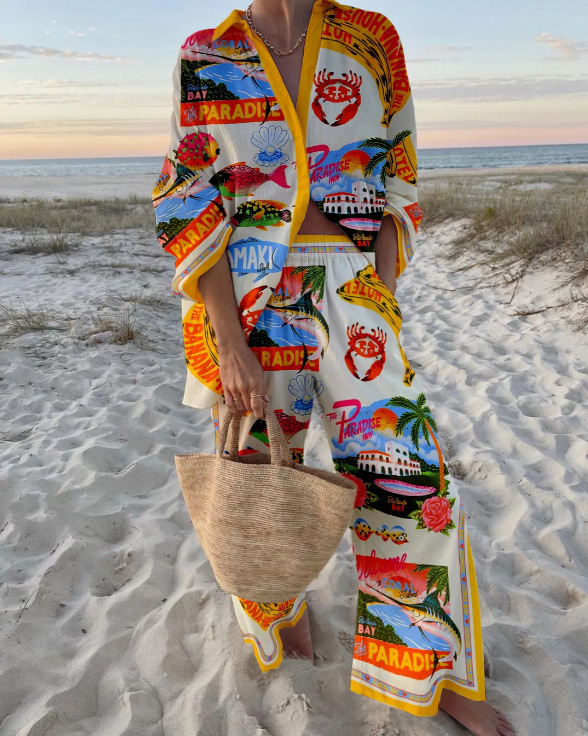 Person wearing a colorful outfit with beach-themed designs on a sandy beach.