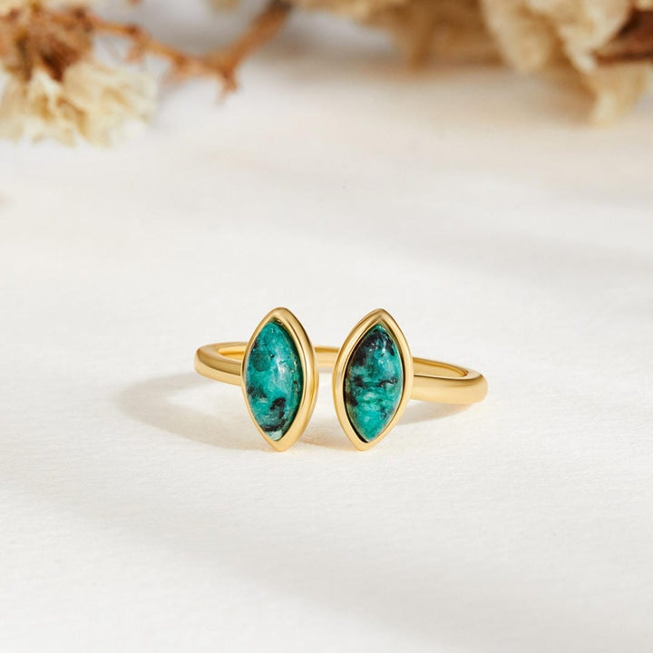Gold ring with green gemstones on a white background