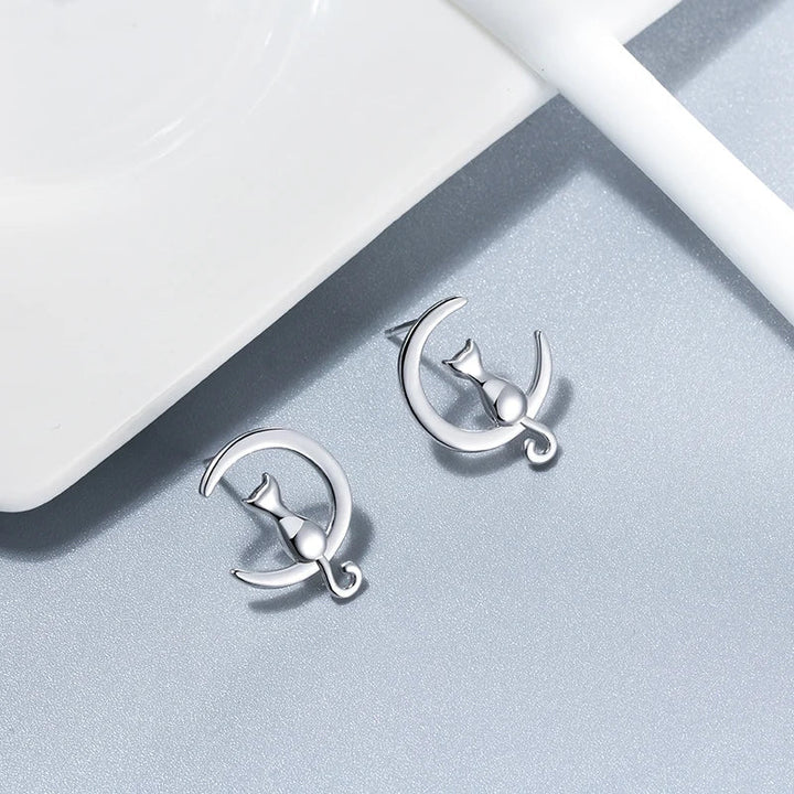 Silver earrings with moon and star design on a light gray surface