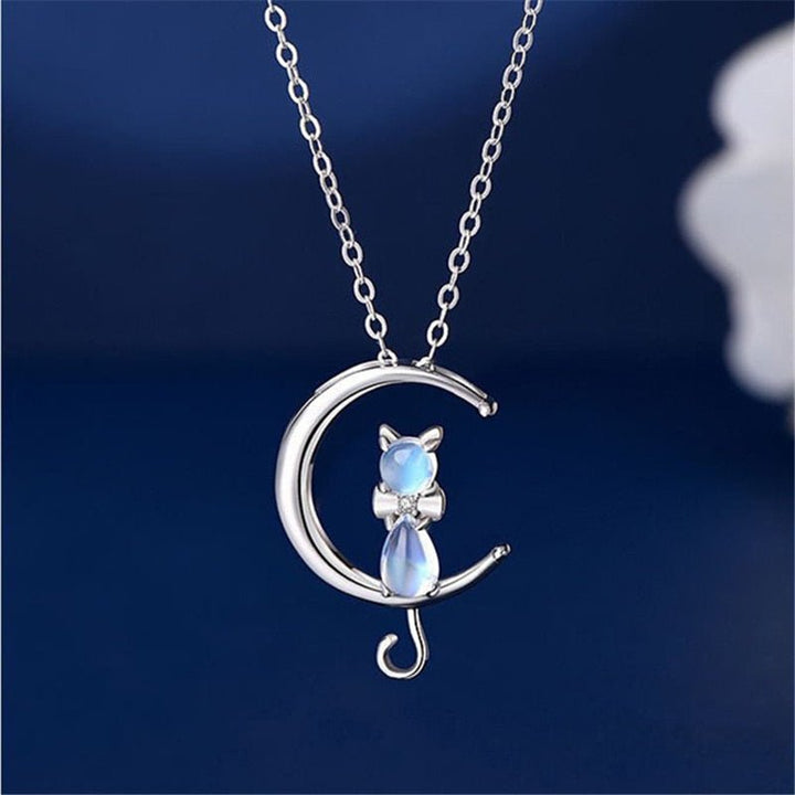 Cat on a moon necklace with a blue gemstone on a dark blue background