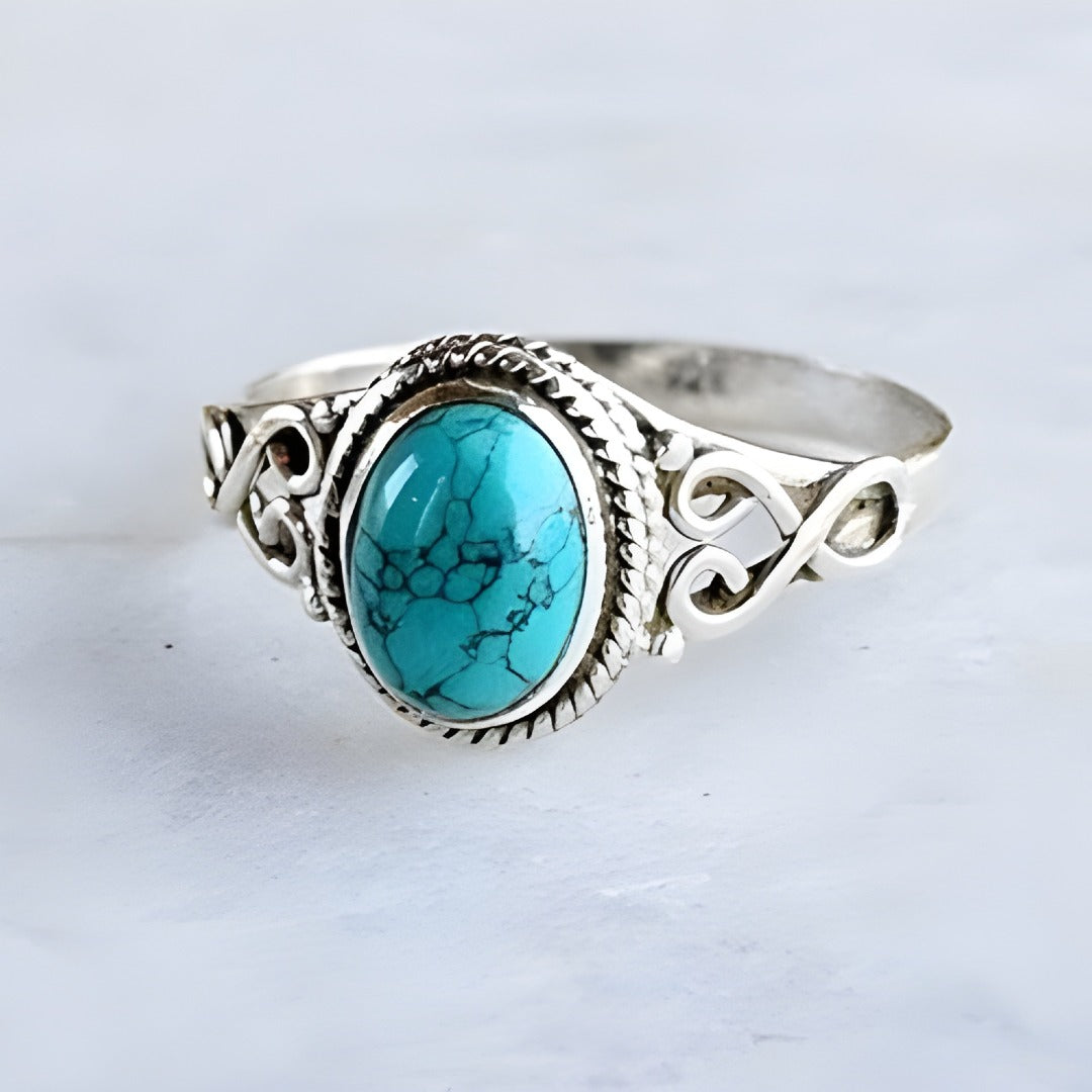 Silver ring with a turquoise stone on a light gray background